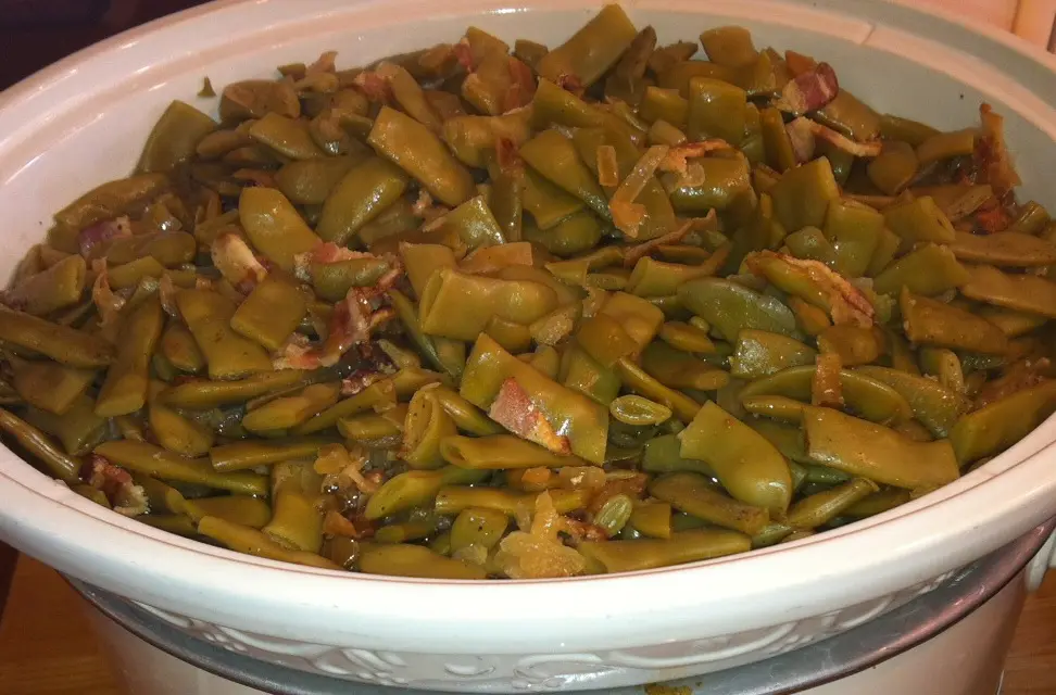 Cooked green beans with bacon in bowl.