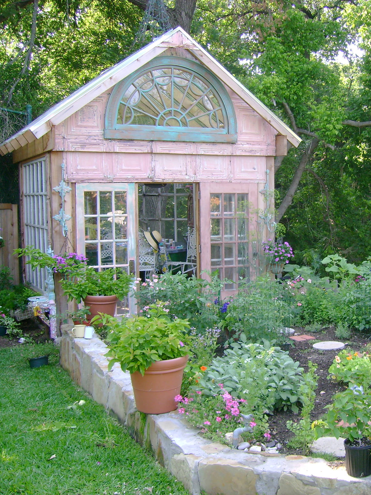Rustic greenhouse surrounded by lush garden.
