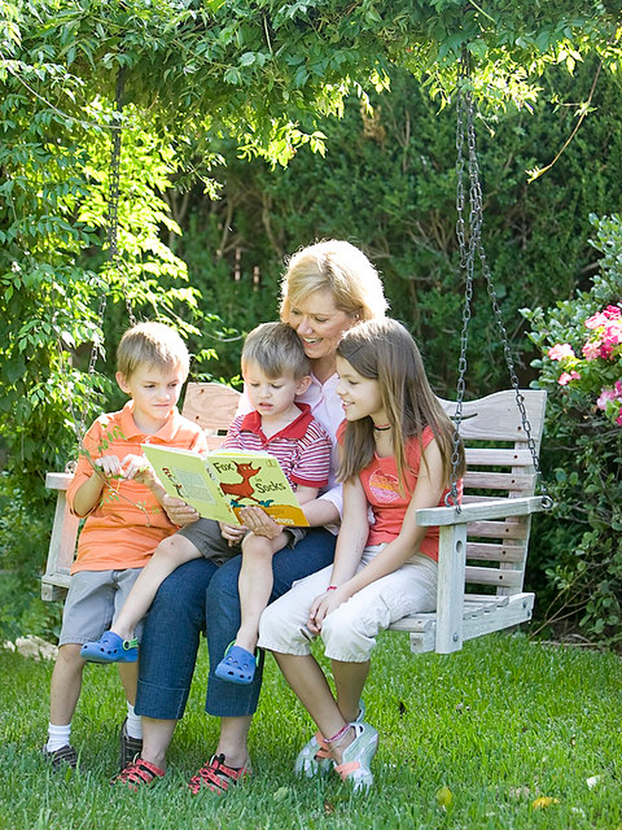 Family reading together on garden swing.