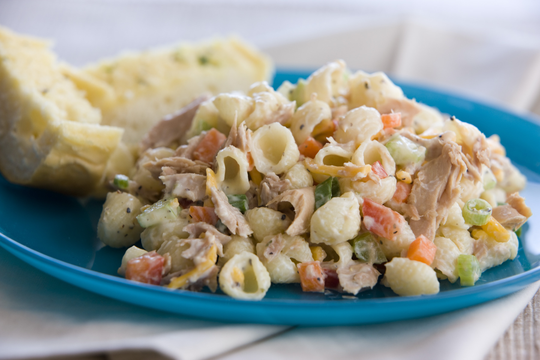 Pasta salad with vegetables and bread slice.