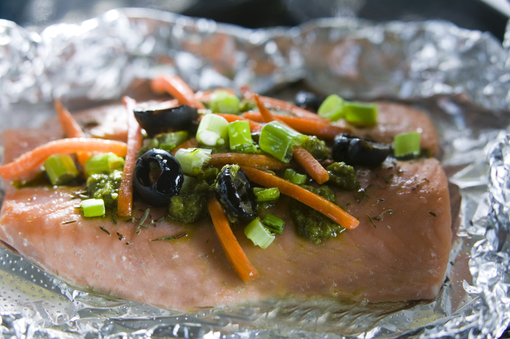 Salmon with vegetables and olives on foil.