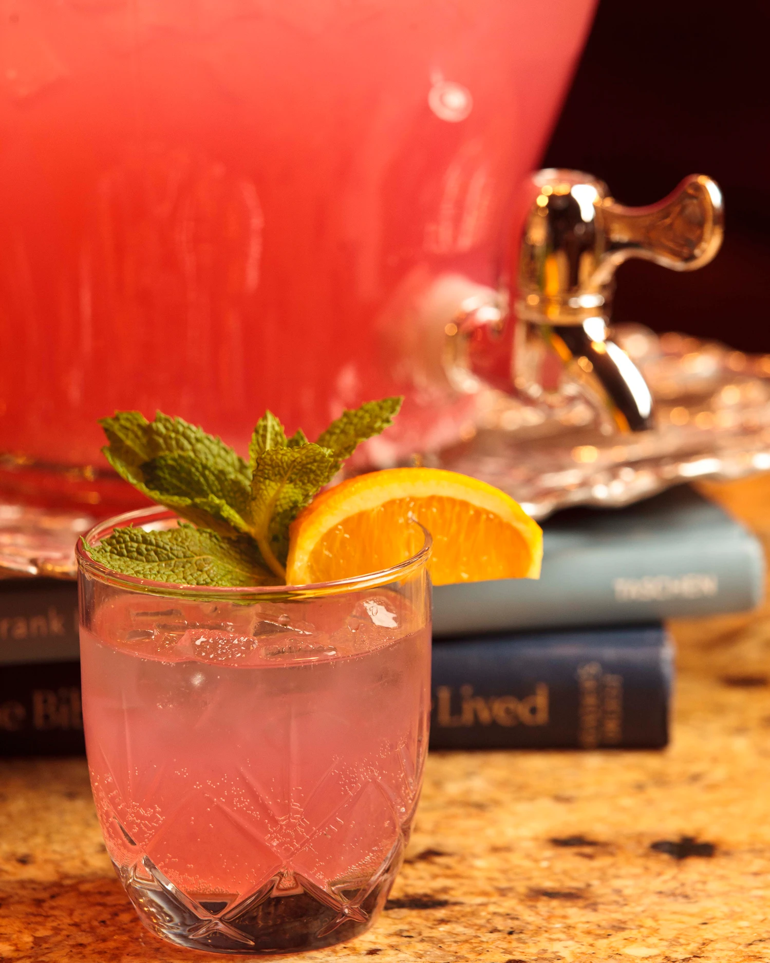 Pink cocktail with mint and orange slice.