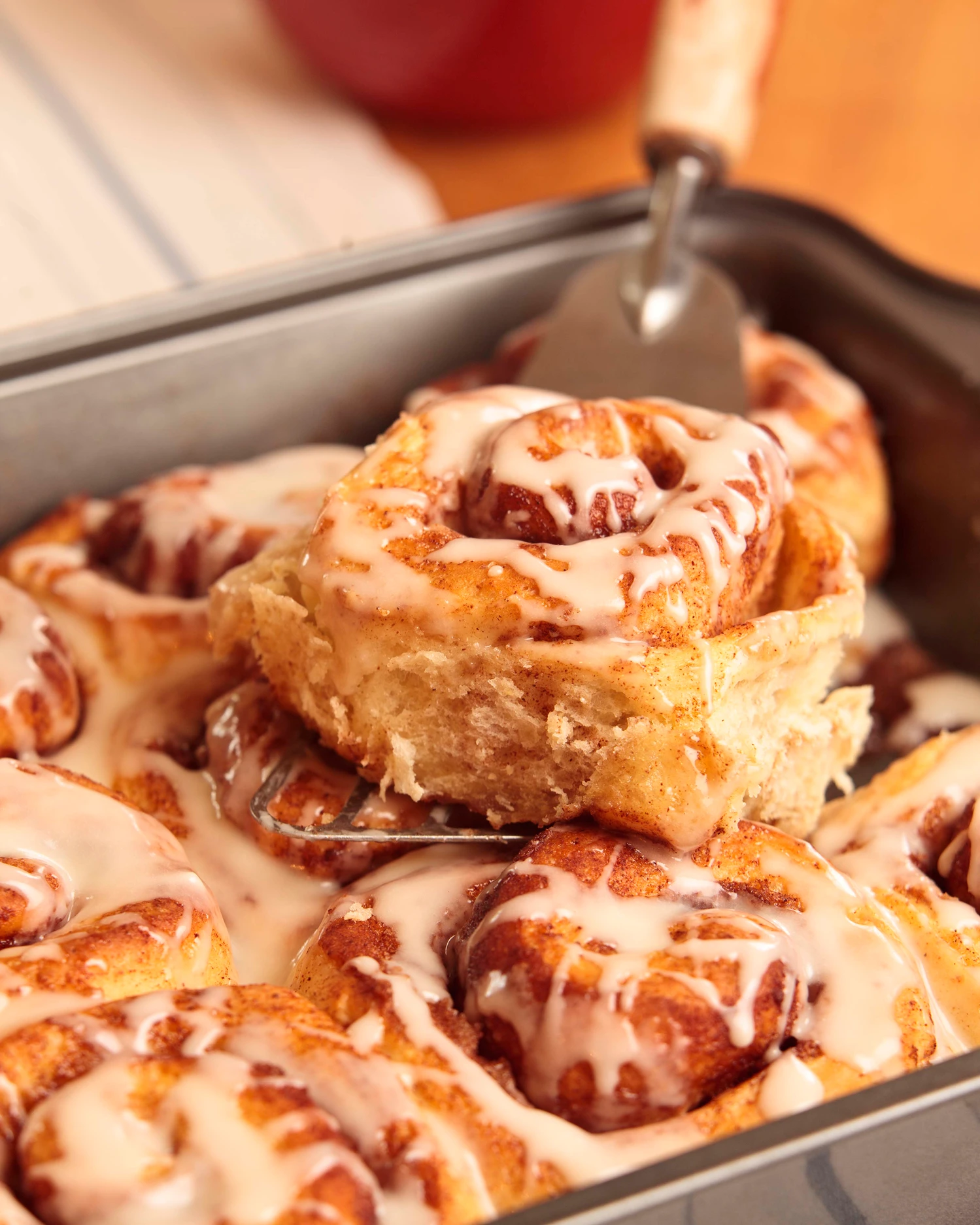 Cinnamon rolls with icing in baking tray.