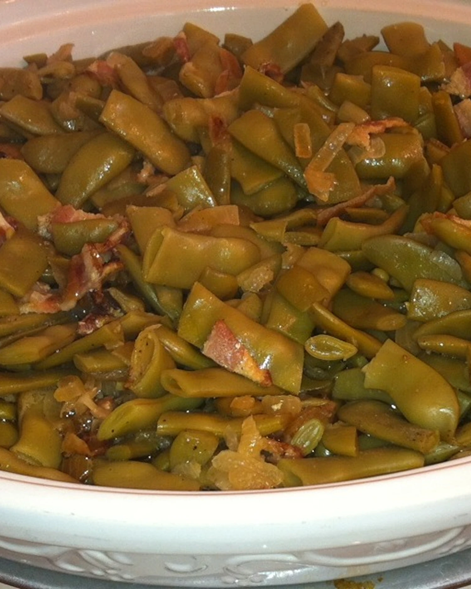 Cooked green beans in a white dish.
